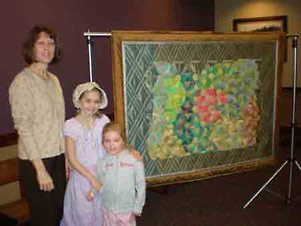 The little girl representing early Oregon settlers, her little sister, and me pose next to the quilt. 
